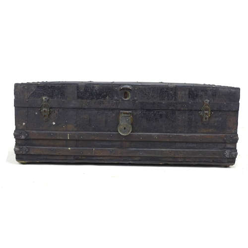 132 - A late Victorian or Edwardian trunk, the wooden carcass bound in dark metal and wooden batons, with ... 