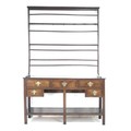 A Georgian oak Welsh dresser of small proportions, plate rack with three shelves and seven metal hoo... 