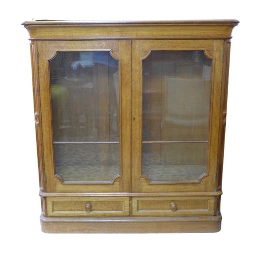 345 - A French late 19th century oak bookcase, twin glazed doors enclosing shelves, over two drawers below... 