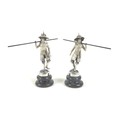 A pair of Burmese silver figures, in traditional dress, holding large poles, raised on circular step... 