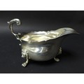 An Victorian silver sauce boat, with scroll handle, scalloped top rim and raised upon three lion hea... 