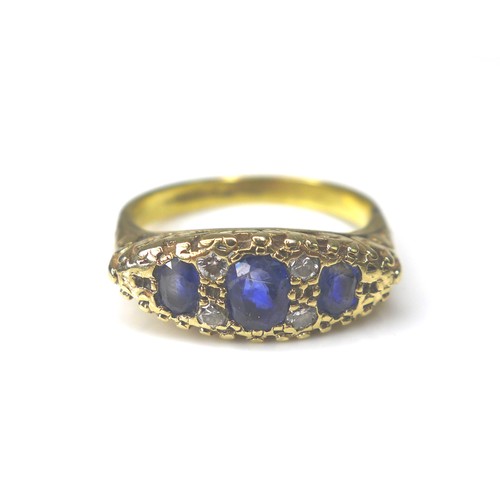 184 - A three stone blue sapphire and diamond ring, the central sapphire 3 by 5mm, four small round cut di... 