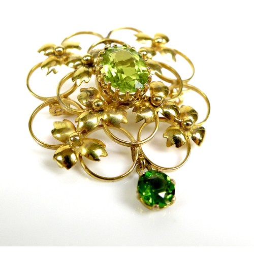 164 - A 9ct gold and green stone openwork brooch, 2.9 by 3.3cm, the lower drop stone of darker hue and mos... 