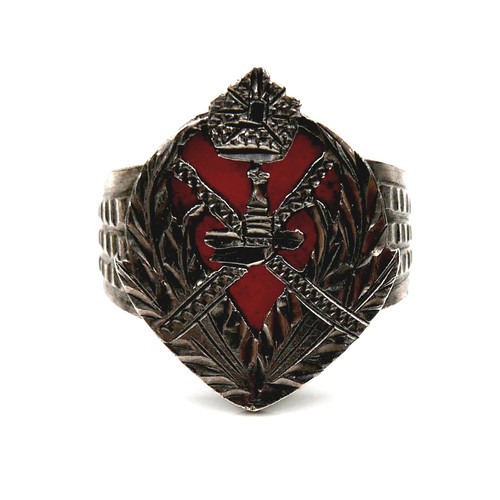 151 - A white metal ring, with carved and pierced crest and red coral backing, 21mm wide, size O/P, 5.9g.