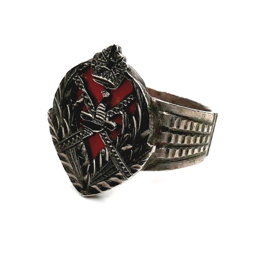 151 - A white metal ring, with carved and pierced crest and red coral backing, 21mm wide, size O/P, 5.9g.