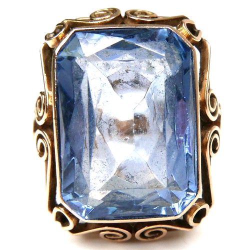 197 - An unmarked yellow gold dress ring, set with an emerald cut blue stone, probably blue topaz, 18.5 by... 