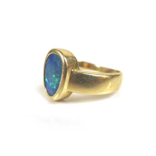 216 - A 14k yellow gold and opal ring, the oviform shaped opal in rub over setting, 10.5 by 7.0mm, on wide... 