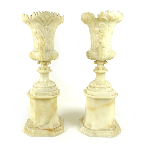 87 - A pair of Italian 19th century alabaster urns, raised on pedestals on an octagonal base, the handles... 