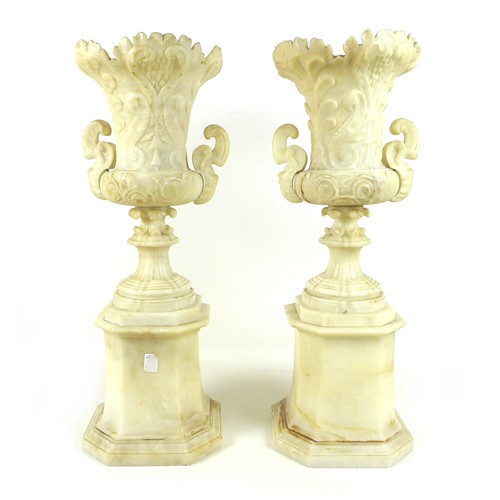 87 - A pair of Italian 19th century alabaster urns, raised on pedestals on an octagonal base, the handles... 