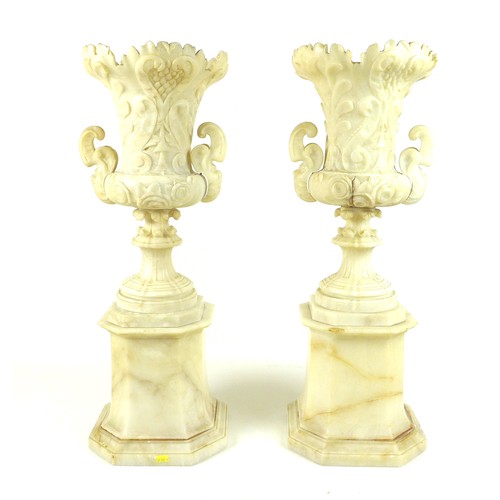 87 - A pair of Italian 19th century alabaster urns, raised on pedestals on an octagonal base, the handles... 