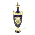 A Coalport twin handled covered vase, cobalt blue ground, overlaid with raised gilding, and a front ... 