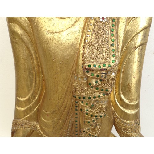 83 - A modern gilt carved wooden sculpture of a Burmese Mandalay Buddha, in standing position with arms o... 