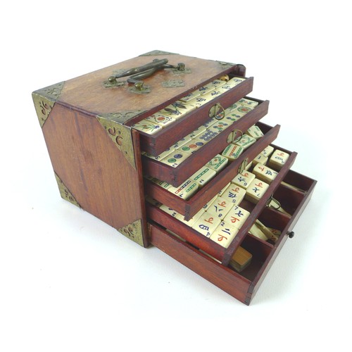 110 - An early 20th century Mahjong set, the case with slide front panel revealing five trays, filled with... 