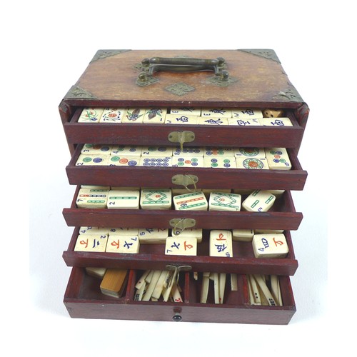 110 - An early 20th century Mahjong set, the case with slide front panel revealing five trays, filled with... 