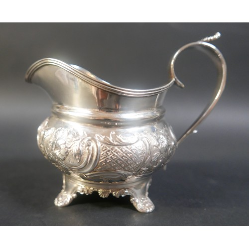 29 - A George III silver cream jug, with a shell mounted scroll handle, repousse decoration to its main b... 