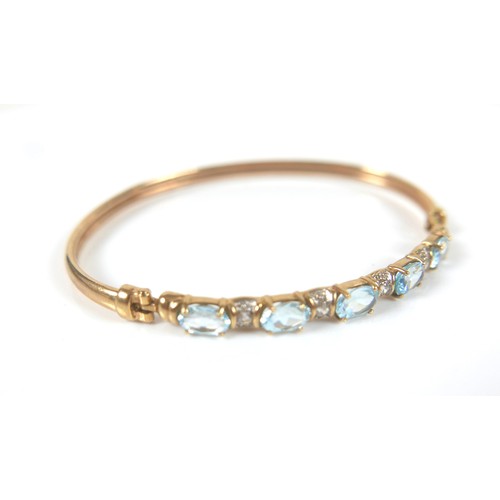 148 - Two gold and gem stone bangles, including a 9ct gold blue topaz bangle, the topaz interspersed with ... 