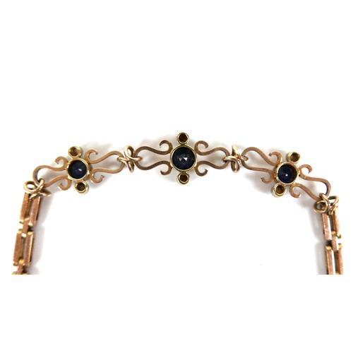 186 - A 9ct yellow gold and sapphire bracelet, with three scrolling panels, each set with a circular facet... 