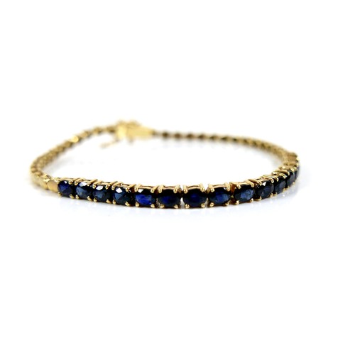 188 - A 14ct yellow gold and sapphire bracelet, set with a row of sixteen oval cut blue sapphires, each 3.... 