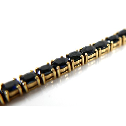 188 - A 14ct yellow gold and sapphire bracelet, set with a row of sixteen oval cut blue sapphires, each 3.... 