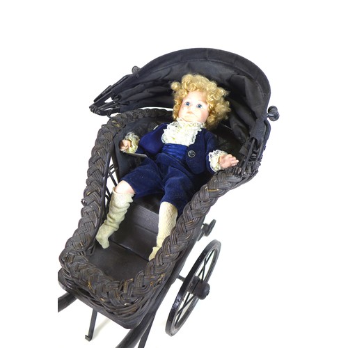 133 - A Victorian style doll's pram, woven wicker painted black, together with a modern bisque headed doll... 