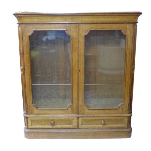 378 - A French late 19th century oak bookcase, twin glazed doors enclosing shelves, over two drawers below... 