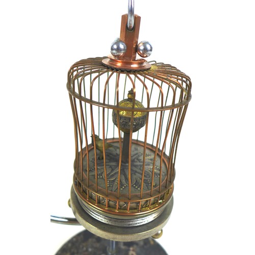 126 - A novelty wind-up clock in the form of a bird in a cage, early 20th century, central rotating orb wi... 