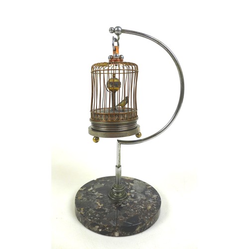 126 - A novelty wind-up clock in the form of a bird in a cage, early 20th century, central rotating orb wi... 