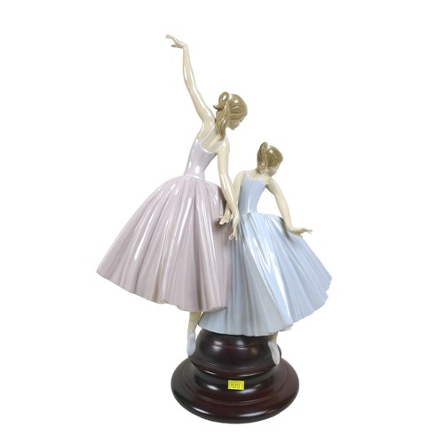 64 - A large Lladro figurine 'Merry Ballet', modelled as two ballerinas, raised on a circular wooden plin... 