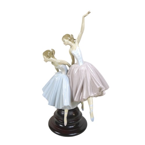 64 - A large Lladro figurine 'Merry Ballet', modelled as two ballerinas, raised on a circular wooden plin... 