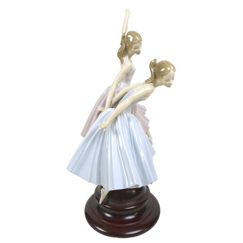 64 - A large Lladro figurine 'Merry Ballet', modelled as two ballerinas, raised on a circular wooden plin... 