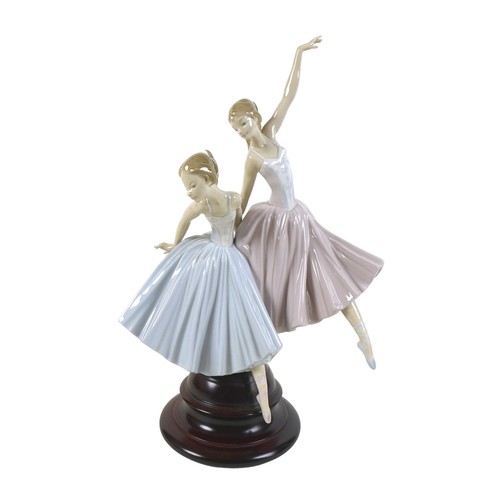 64 - A large Lladro figurine 'Merry Ballet', modelled as two ballerinas, raised on a circular wooden plin... 