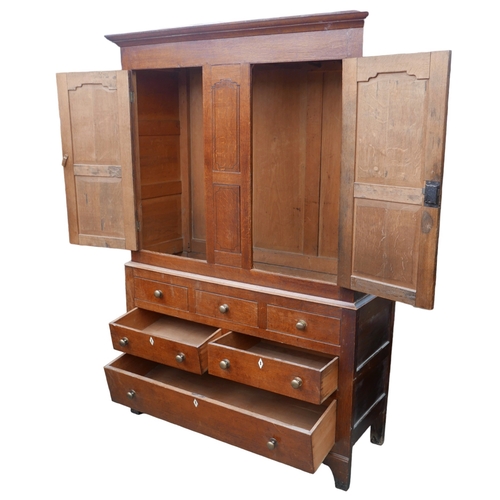 411 - A 19th century oak over pine cupboard, upper section with two panelled doors opening to reveal a han... 