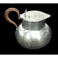 An Edwardian silver hot water jug, with hinged lid, wicker bound handle, William Comyns & Sons Ltd. ... 