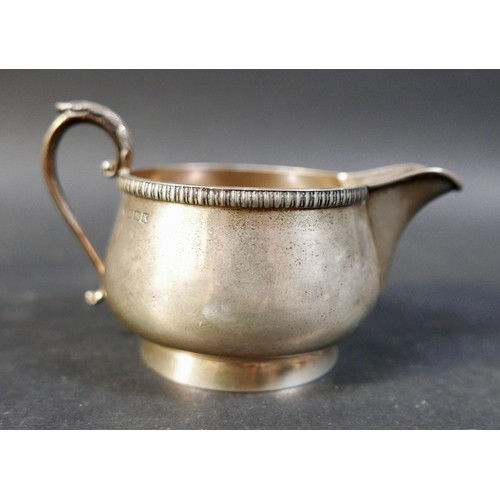 62 - A group of four silver items, comprising a milk jug, a sugar bowl, a tankard mustard with plated spo... 