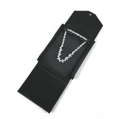 195 - A zircon and plated metal necklace, formed of leaves, 37cm long, in black satin case.