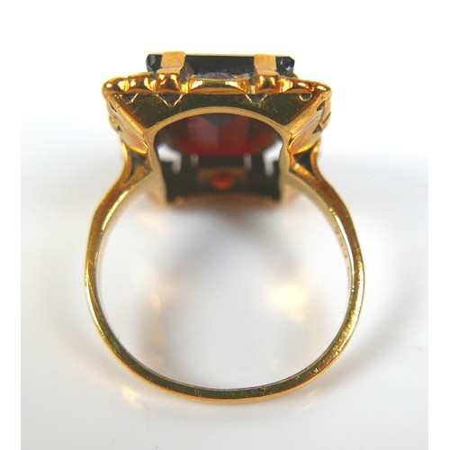 200 - An 18ct yellow gold dress ring, set with an emerald cut red stone, possibly garnet, 14.3 by 11.2 by ... 