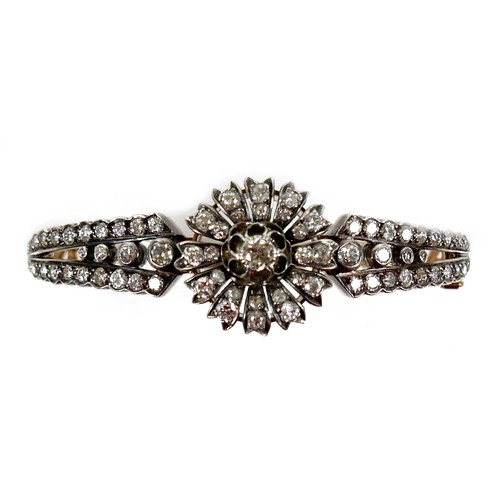 302 - A French early 20th century 18ct yellow gold and white metal diamond hinged bangle, the central flow... 