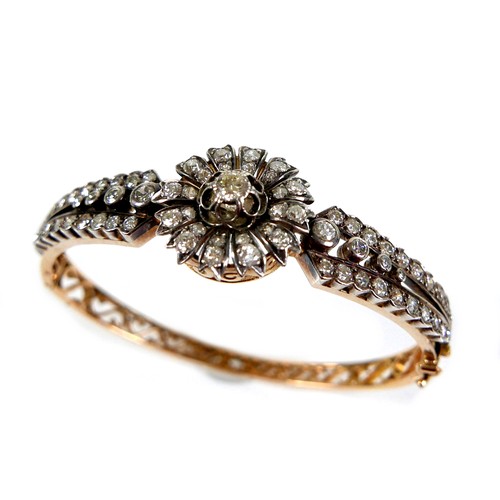 302 - A French early 20th century 18ct yellow gold and white metal diamond hinged bangle, the central flow... 