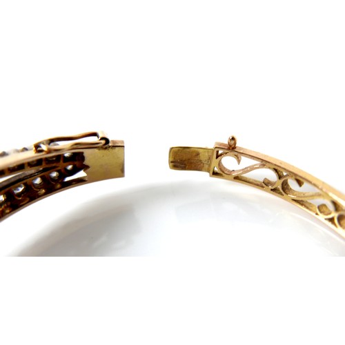 302 - A French early 20th century 18ct yellow gold and white metal diamond hinged bangle, the central flow... 