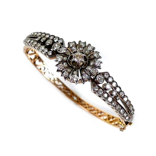 302 - A French early 20th century 18ct yellow gold and white metal diamond hinged bangle, the central flow... 