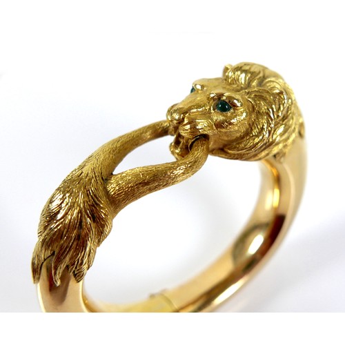 308 - An 18ct yellow gold hinged bangle, formed as a lion grasping it's tail in it's jaws, with inset cabo... 