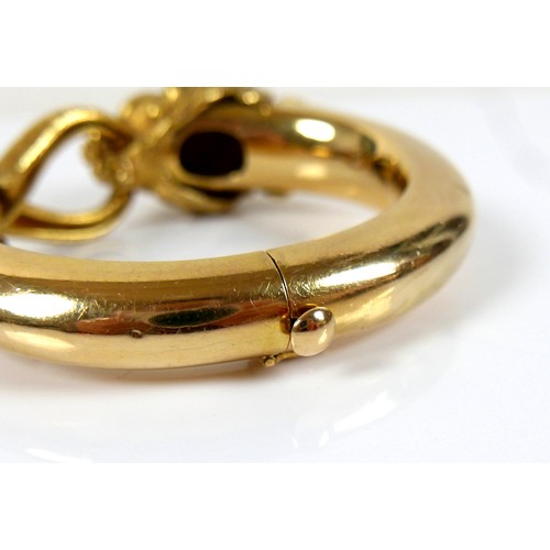 308 - An 18ct yellow gold hinged bangle, formed as a lion grasping it's tail in it's jaws, with inset cabo... 