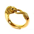 An 18ct yellow gold hinged bangle, formed as a lion grasping it's tail in it's jaws, with inset cabo... 