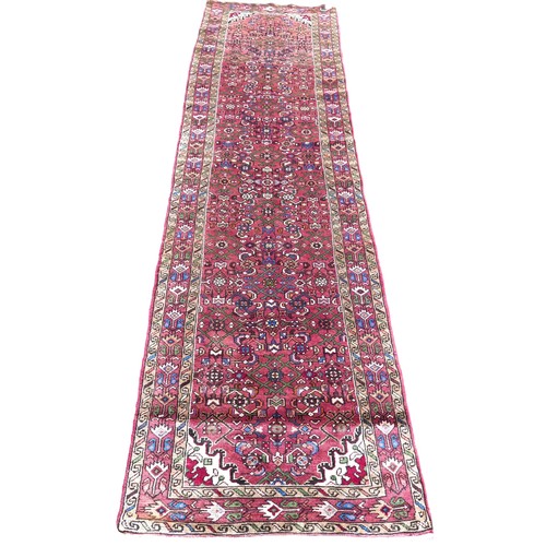 555 - A Persian hand knotted runner, red ground, floral decoration, 365 by 100cm.