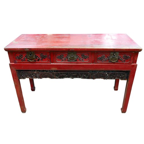 552 - A Chinese red lacquer three drawer hall table with a figural carved frieze, 138 by 56 by 88cm.