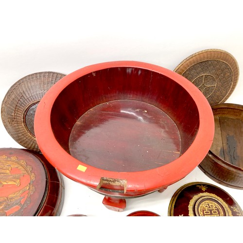 15 - A collection of eight Chinese wooden and rattan bowls, the largest painted red and raised on four le... 
