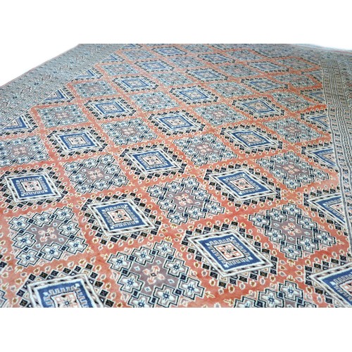 563 - A hand knotted woolen rug with a pink field and geometric design, 302 by 224cm.