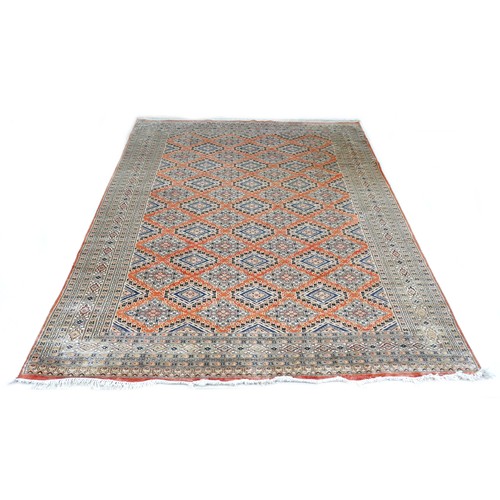 563 - A hand knotted woolen rug with a pink field and geometric design, 302 by 224cm.