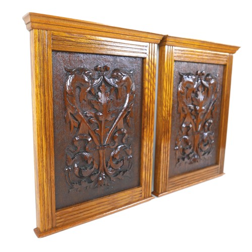 251 - A pair of Arts and Crafts carved wooden panels, mounted in oak frames, each 26.5 by 37cm high, with ... 