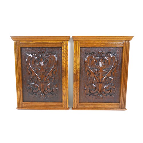 251 - A pair of Arts and Crafts carved wooden panels, mounted in oak frames, each 26.5 by 37cm high, with ... 